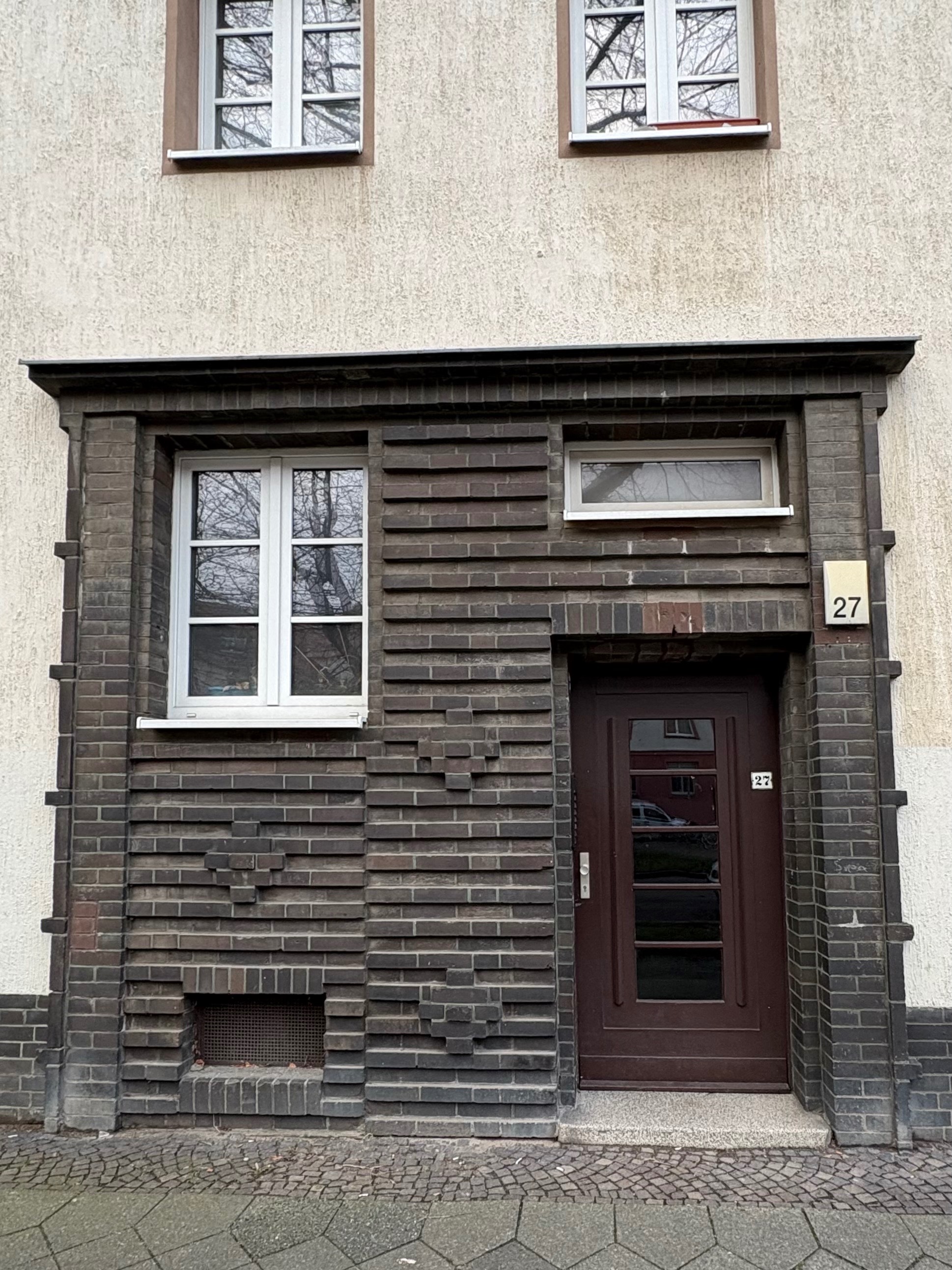 Subtle expressionist ornamentation around the entrance of an apartment building